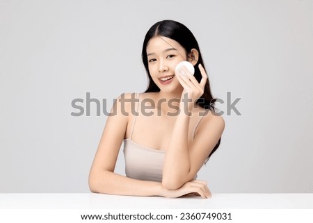 Portrait of young beautiful Asian woman with healthy facial skin using cotton pad for removing make up cosmetic isolated on white background. Royalty-Free Stock Photo #2360749031