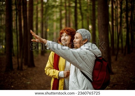 Cheerful pensioner female friends tallking and laughing in the autumn park. Lifestyle concept.
