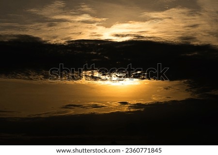 A picture of the sunset sky in the evening with clouds in dark shadows that are colorful, and peaceful.