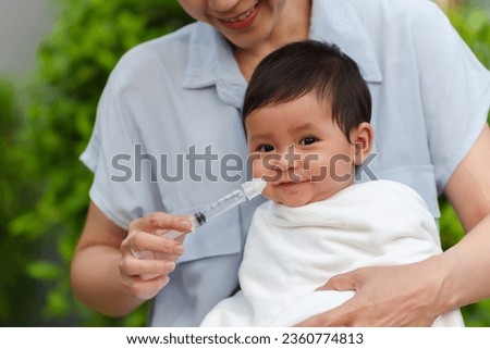 mother making nasal wash for her infant with syringe and saline. happy cleaning baby nose Royalty-Free Stock Photo #2360774813