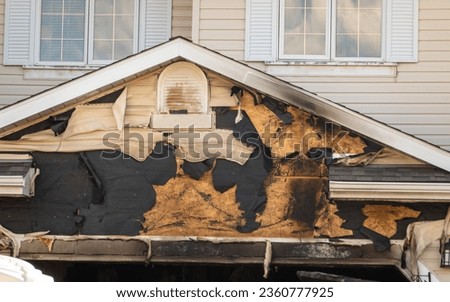 A close-up view of a neighborhood garage roof, which bears the scars of recent accidental fire damage, expertly extinguished by firefighters in the midst of a tranquil autumn. Royalty-Free Stock Photo #2360777925