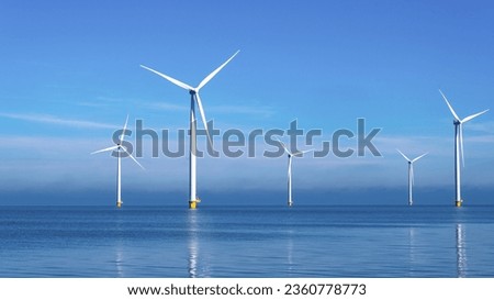Windmill park with clouds and a blue sky, wind mill turbines in the ocean aerial view of a wind farm in the Nehterlands production clean energy Royalty-Free Stock Photo #2360778773
