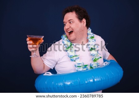 Funny fat man posing with an inflatable ring. Blue background. Vacations and holidays.
