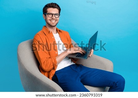 Photo of attractive nice guy sitting comfort chair hold use wireless netbook networking isolated on blue color background Royalty-Free Stock Photo #2360793319