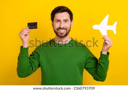 Photo of satisfied man wear stylish sweatshirt hands showing bank card recommend buy tickets online isolated on yellow color background
