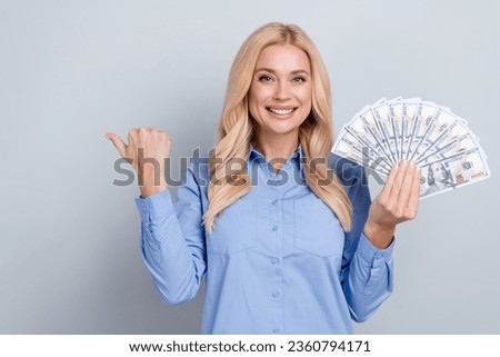 Photo of stunning positive corporate lady toothy smile hold dollar bills direct finger empty space isolated on grey color background