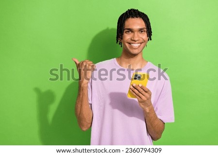 Photo of handsome blogger man hold smart phone direct finger empty space promo isolated on green color background