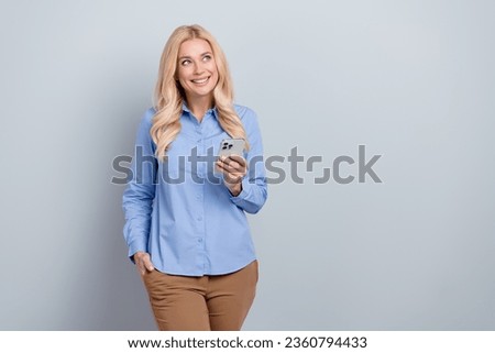 Photo of dreamy agent worker young lady wearing blue shirt brown pants read news phone look novelty isolated on grey color background