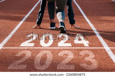 happy new year 2024 symbolizes the start of the new year. Rear view of a man preparing to run on the athletics track engraved with the year 2024. The goal of Success.Getting ready for the new year Royalty-Free Stock Photo #2360804875