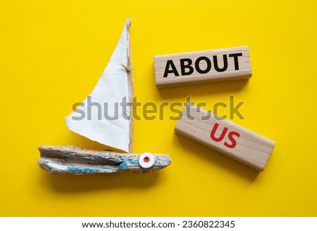 About us symbol. Concept word About us on wooden blocks. Beautiful yellow background with boat. Business and About us concept. Copy space
