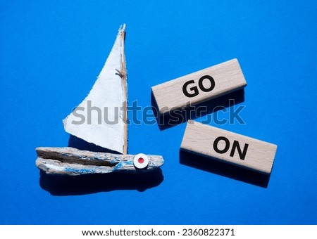 Go on symbol. Wooden blocks with words Go on. Beautiful blue background with boat. Business and Go on concept. Copy space.