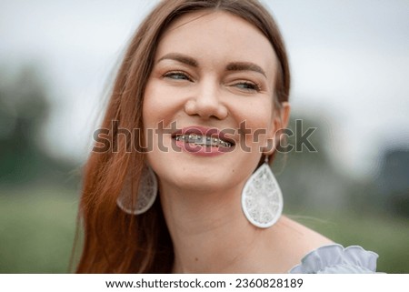 The smile of a young and beautiful girl with braces on her white teeth. Straightening of crooked teeth with the help of a bracket system. Malocclusion. Dental care. Smooth teeth and a beautiful smile Royalty-Free Stock Photo #2360828189