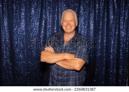 Photo Booth. A man smiles and poses for his pictures to be taken while in a Photo Booth at a Wedding. Photo Booths are popular at Weddings, Birthdays and all events both Public and Private. Fun Times.