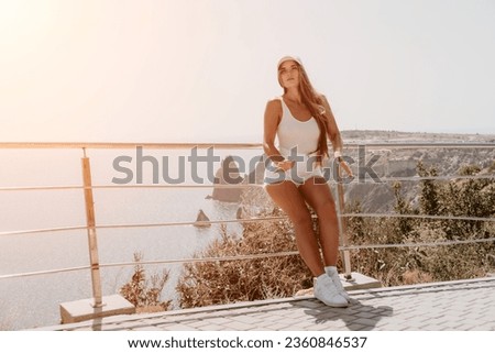 Woman summer travel sea. Happy tourist enjoy taking picture outdoors for memories. Woman traveler posing over sea bay surrounded by volcanic mountains, sharing travel adventure journey