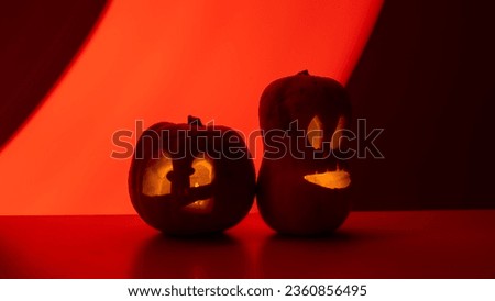 Two jack-o-lanterns glow in the dark on a red background. Halloween decoration.