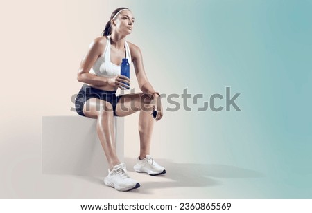 Fit woman relaxes and drinking water on seaside promenade after Workout training. Royalty-Free Stock Photo #2360865569