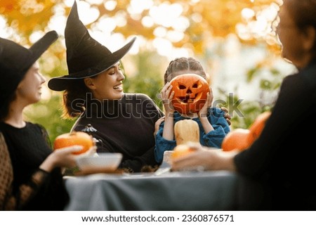 Happy family preparing for Halloween. Mother, grandmother and children carving pumpkins in the backyard of the house.