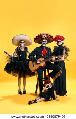 Adorable skeleton posing on yellow background. Happy family with Halloween creative makeup celebrating looks like mexicans. trick or treat.Concept of autumn, holidays, horror, body art. Ad.