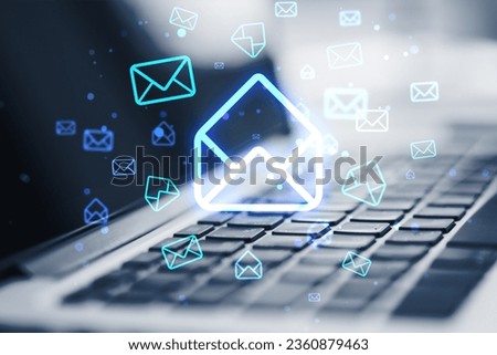 Close up of laptop on desk with glowing email letter icons on blurry background. Communication and business message concept