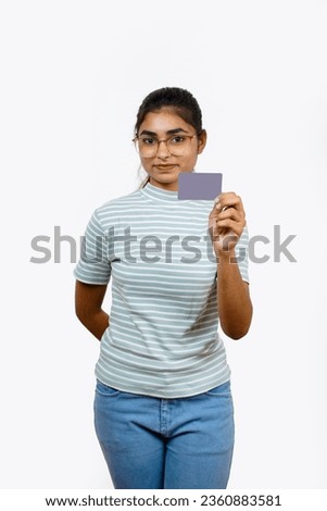 Beautiful young blonde woman holding up a credit card while avoiding her eyes from the copy space in the picture pose.