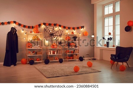 Interior of spacious room in house which is decorated with decorations in Halloween style. Room for Halloween party is decorated with pumpkins, lanterns, cobwebs, spiders, balloons and skeleton.