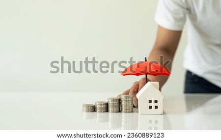 Model house and raised pile with hand holding an umbrella on white background, financial insurance and safe investment concept. Close-up pictures Royalty-Free Stock Photo #2360889123