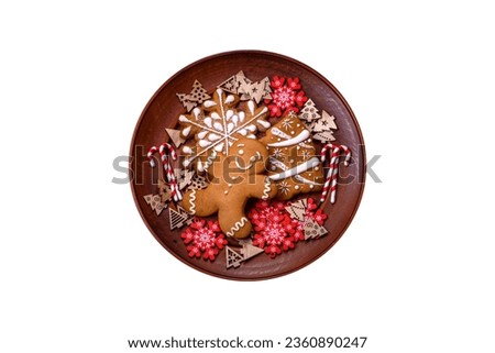 Beautiful gingerbread on a brown ceramic plate with Christmas tree decorations on a dark concrete background. Getting home ready for Christmas