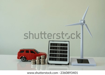 blue solar panel Windmill and car model with pile of coins on white table, energy saving concept.