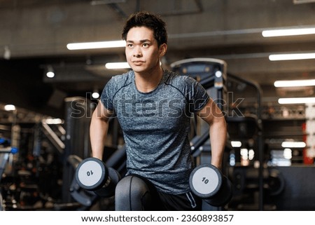 Young Asian man training with dumbbells