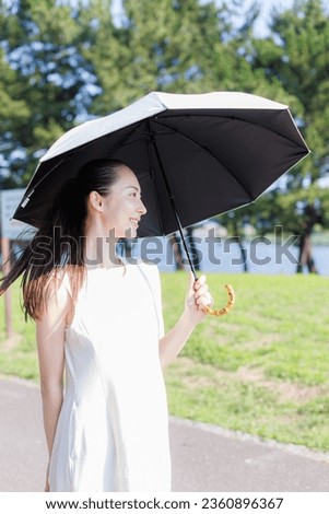 Young Asian woman with an umbrella walking in the park