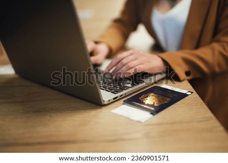 Woman with UK passport is waiting for her flight. Royalty-Free Stock Photo #2360901571