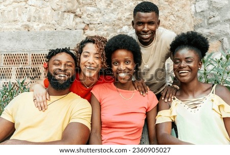 Young cheerful group of multiracial people sitting outdoors - Lifestyle concept with boys and girls having fun hanging out on city street