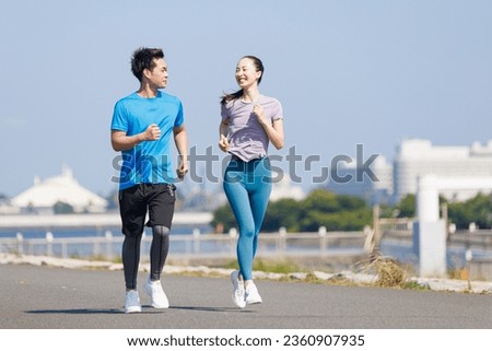 Young Asian adults jogging outdoors Royalty-Free Stock Photo #2360907935