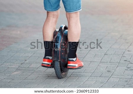 Electric unicycle (EUC), personal mobility. Man in shorts rides on electric mono wheel down the city street in summer season. Man cycling on monowheel. Boy travel on mono wheel.  Royalty-Free Stock Photo #2360912333