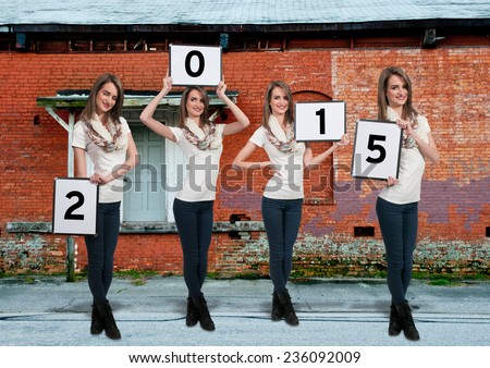 Beautiful young quadruplet woman holding up New Years signs