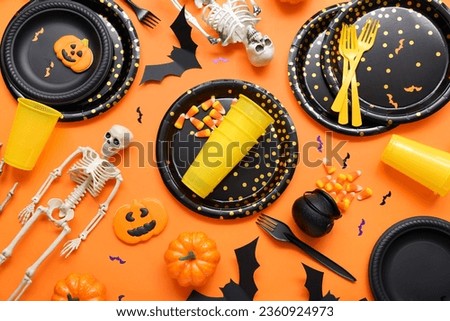 Festive table setting with Halloween decorations on orange background