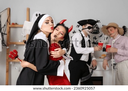 Female friends in costumes hugging at Halloween party