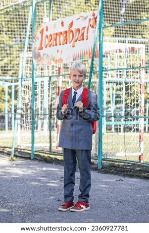 The inscription on the poster is in Russian - September 1st! Full-length portrait of a third-grader in a school uniform and with a backpack Royalty-Free Stock Photo #2360927781