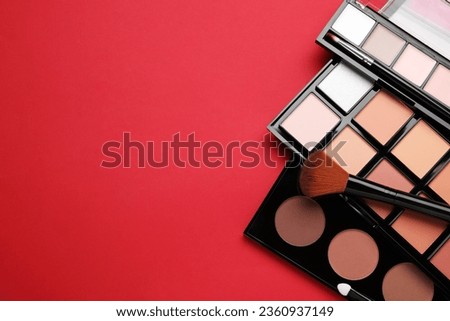 Colorful contouring palettes and brush on red background, flat lay with space for text. Professional cosmetic product