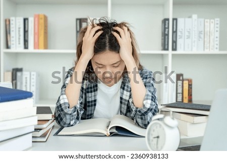 Asian student woman have anxiety because of exams, female prepare for test and learning lessons in the library. stress, despair, haste, misunderstanding reading, discouraged, expectation, knowledge Royalty-Free Stock Photo #2360938133