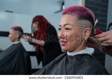 Asian woman with pink hair getting a haircut in a barbershop.  Royalty-Free Stock Photo #2360942801