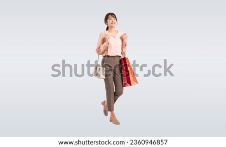Asian middle-aged woman walking cheerfully with shopping bags