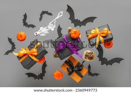 Flying gift boxes, paper bats, skeleton and skull for Halloween celebration on grey background