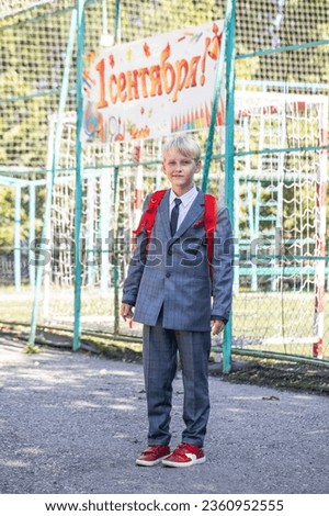 The inscription on the poster is in Russian - September 1st! Full-length portrait of a third-grader in a school uniform and with a backpack Royalty-Free Stock Photo #2360952555