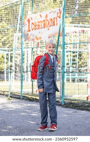 The inscription on the poster is in Russian - September 1st! Full-length portrait of a third-grader in a school uniform and with a backpack Royalty-Free Stock Photo #2360952597