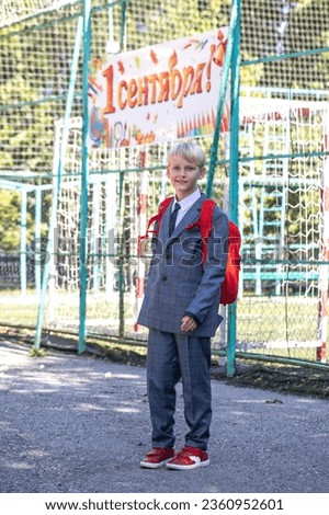 The inscription on the poster is in Russian - September 1st! Full-length portrait of a third-grader in a school uniform and with a backpack Royalty-Free Stock Photo #2360952601