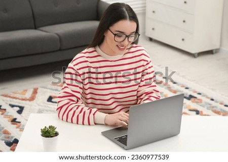 Woman using laptop at white table indoors