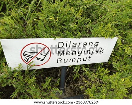 Warning sign "No stepping on grass" with a green grass background at a mosque in the Bogor area