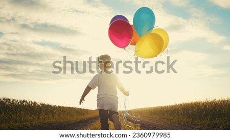 little baby boy run with balloons in the park in nature. happy family holiday birthday kid dream concept sun. lifestyle little baby with colorful balloons run with the road in the field park