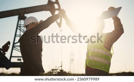 handshake business oil contract. handshake worker and businessman shaking hands against backdrop of an oil pump. oil extraction business concept. silhouette handshake sunlight business contract Royalty-Free Stock Photo #2360979989